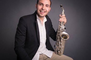 Gülümseyen saksafoncu adam karanlık arka plana karşı izole. Stüdyo portresini kapat.