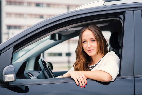 微笑的女人肖像坐在她的车里在城市 已筛选的图像 — 图库照片