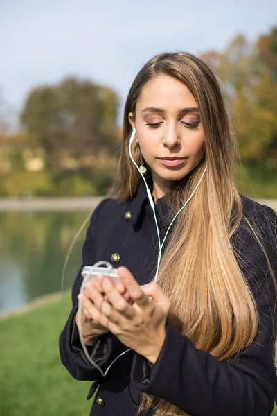 Giovane donna bionda all'aperto in un parco in autunno utilizzando smart phon — Foto Stock