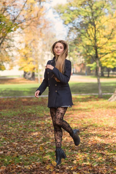 Mujer rubia joven saltando al aire libre en un parque en otoño . — Foto de Stock