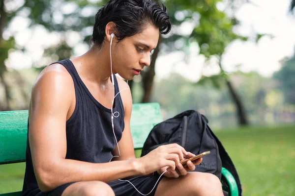 バンコクのルンピニ公園で屋外で運動した後 市内の公園内でスマートフォンを使用する男性 — ストック写真