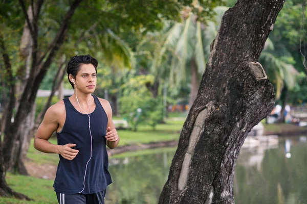 Fitness man running in city park with earphones