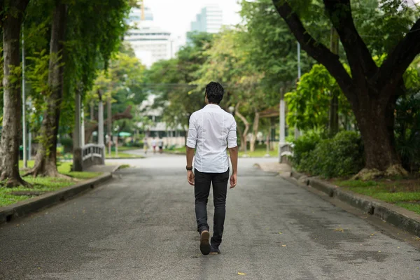 rear view of young man walking in Lumpini Park. Bangkok, Thailand.