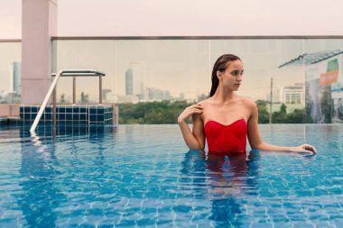 Yüzme havuzunda kırmızı mayo giyen güzel kadın portresi.