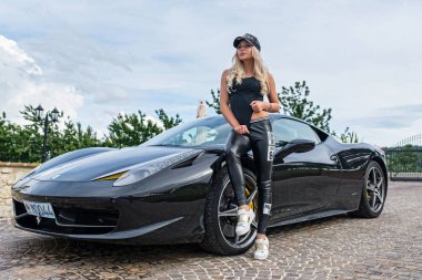 San Marino, İtalya - 21 Haziran 2016: Ferrari 458 arabasıyla poz veren genç güzel kadın