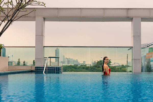 Beautiful woman portrait wearing red swimsuit in swimming pool.