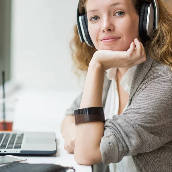 Zakenvrouw portret tijdens het werken met haar laptop en listeni — Stockfoto