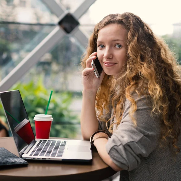 Młoda uśmiechnięta bizneswoman rozmawiająca przez telefon z gorącym napojem — Zdjęcie stockowe