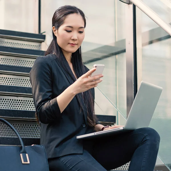 Joven Empresaria Que Trabaja Con Portátil Mientras Usa Teléfono Inteligente — Foto de Stock