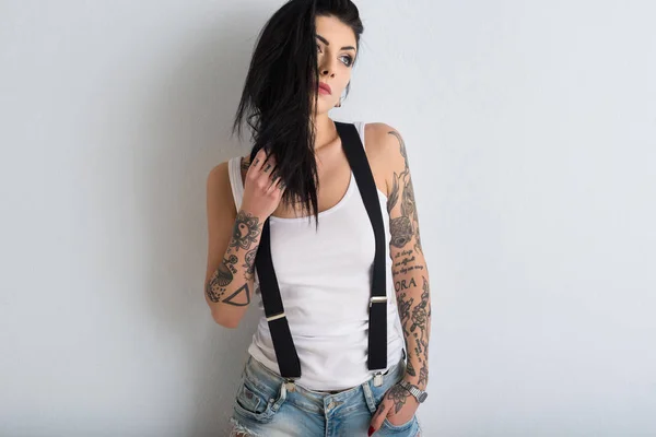 Kvinna porträtt med tatuering mot vit vägg bakgrund. — Stockfoto