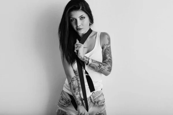 Retrato de mujer con tatuaje y tirantes contra pared blanca. Bl —  Fotos de Stock