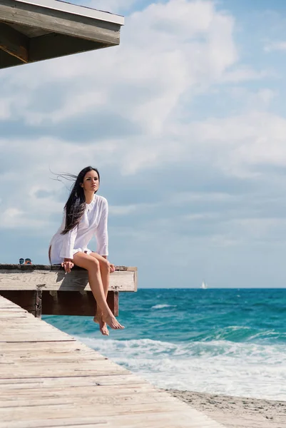 Beautiful woman full body portrait sit on a lifeguard tower. Hollywood beach in Miami, florida.