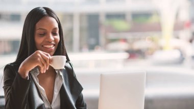 Smiling businesswoman portrait working with notebook while drinking coffee outdoors in Milan.