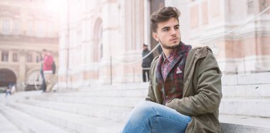 Genç adam portresi İtalya 'nın Bologna kentindeki San Petronio Katedrali' nin merdivenlerinde oturuyor. Kentsel yaşam tarzı kavramı.