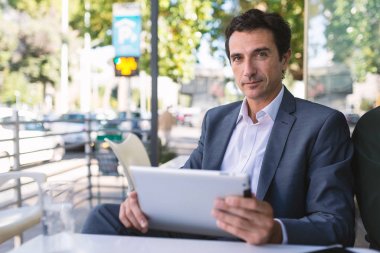 Kendine güvenen orta yaş işadamı portre Roma, İtalya'da açık havada takım elbise giyen tablet kullanarak. Arka plan olarak modern bina. 
