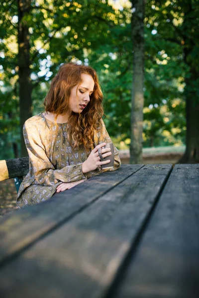 秋天在公园里 年轻的红发女郎从户外的杯子里喝酒的亲密画像 浅景深 — 图库照片