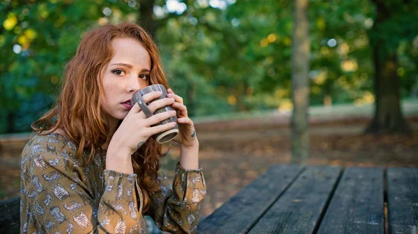 가을에 공원에서 야외에서 컵에서 마시는 여자의 친밀한 초상화 피사계 — 스톡 사진