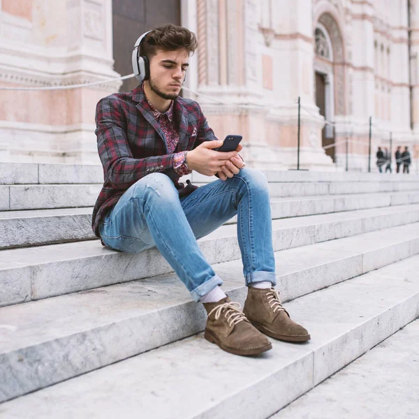 イタリアボローニャ市中心部のサン ペトロニオ大聖堂の前でヘッドフォンで音楽を聴く若い男の肖像画 — ストック写真