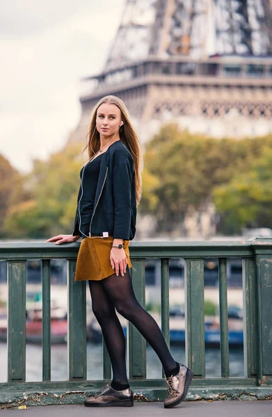 Young beautiful woman full body portrait with Eiffel tower in the background in autumn. Paris, France.