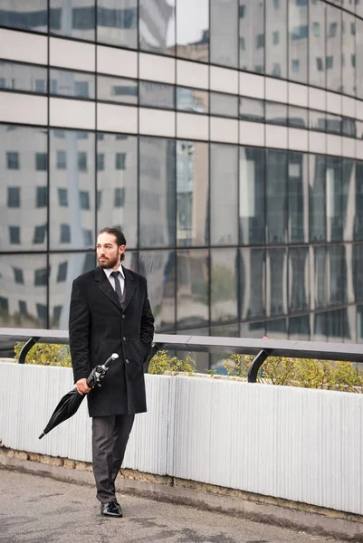 Young businessman full body portrait walking at the Defense District. Paris, France.