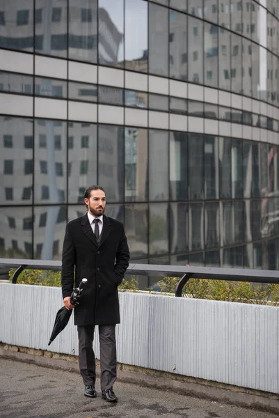 Young businessman full body portrait walking at the Defense District. Paris, France.