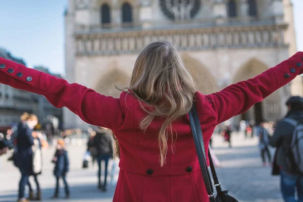 Gelukkige jonge blonde vrouw die haar armen verspreidt met de Notre Dame Cath — Stockfoto