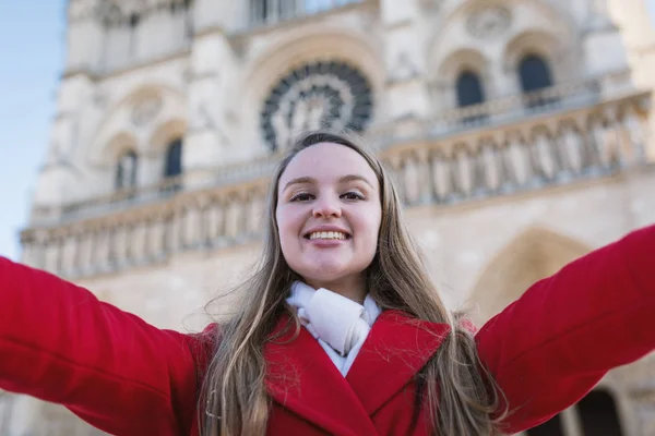 Happy young blonde woman spreading her arms with Notre Dame Cath