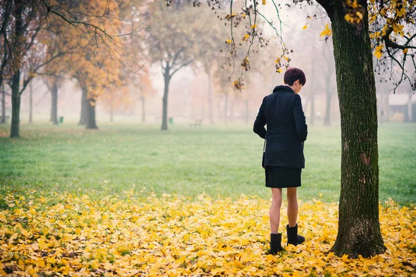 一个红头发的年轻女子在公园里散步 从后面看 — 图库照片