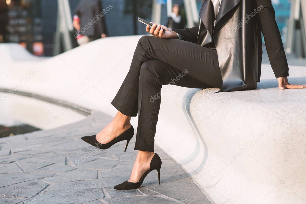 Detail of businesswoman portrait outdoors in Milan while using smart phone.