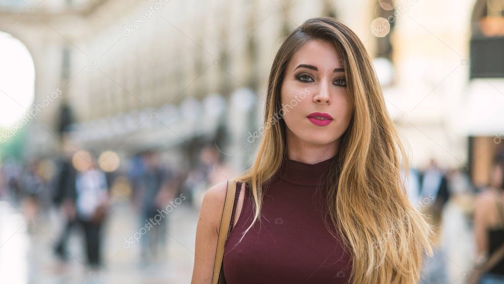 Portrait of young blonde woman inside Galleria Vittorio Emanuele II shopping gallery in Milan, Italy