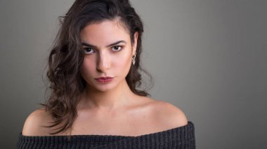 Gri arka plan karşı kendinden emin samimi genç kadın stüdyo portre.