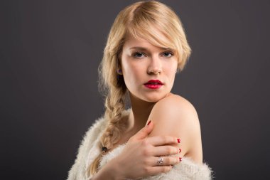 Sensual beautiful woman studio portrait with long blonde hair wearing fur.