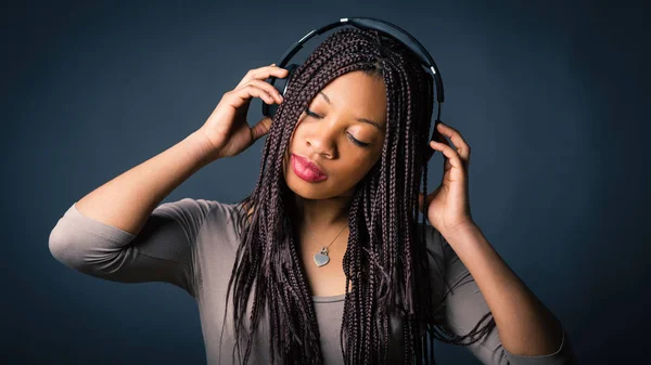 African young woman studio portrait with braids listening to mus