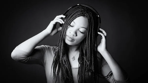 Africaine jeune femme studio portrait avec tresses écoute mus — Photo