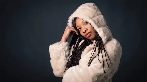 African young woman studio portrait with braids and hood against