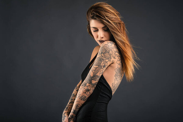 Intimate woman studio portrait with long black dress and tattoos