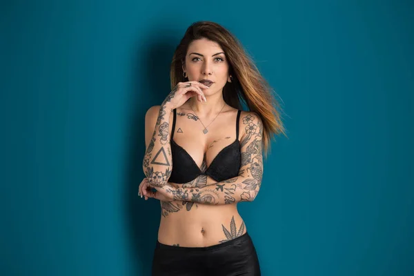 Vacker kvinna Studio porträtt med tatuering mot blå backgro — Stockfoto