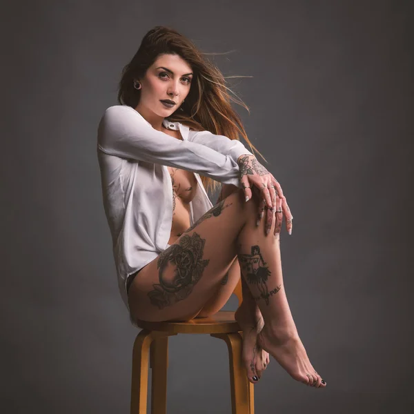 Intieme vrouw studio portret met wit overhemd en tatoeages tegen — Stockfoto