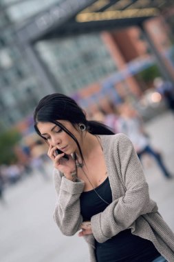 Potsdamer Platz 'da telefonla konuşan genç bir kadın portresi. Ol