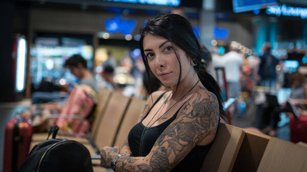 Young brunette tattooed woman portrait at the airport.