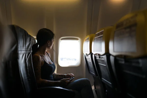 Mladá žena portrét dívá z okna uvnitř letadla. — Stock fotografie