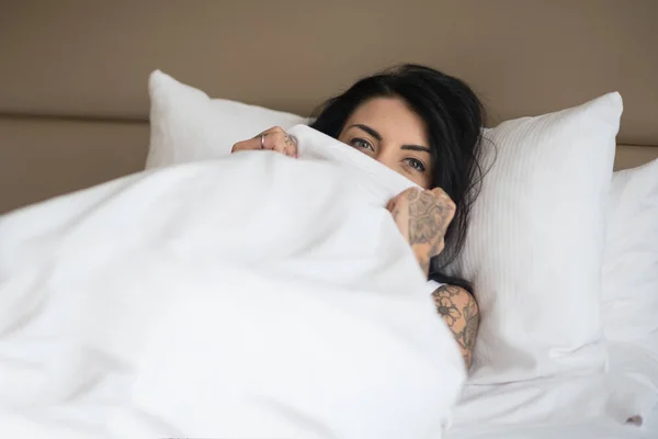 Funny young woman close up portrait laying on her bed and hiding — Stock Photo, Image