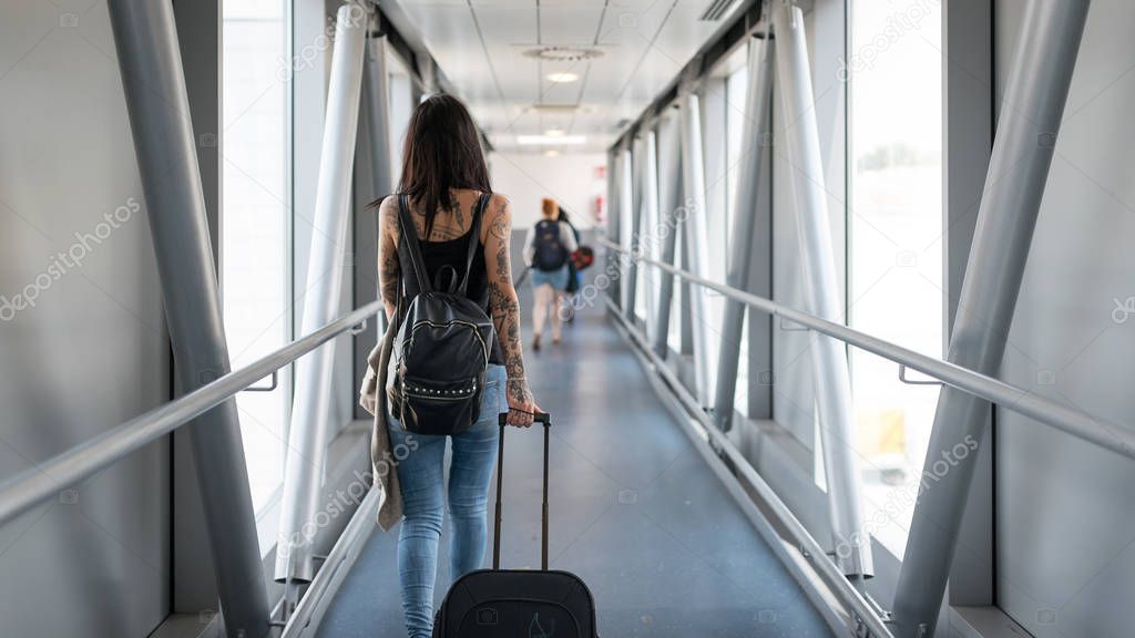 Young brunette tattooed woman back view at the airport.