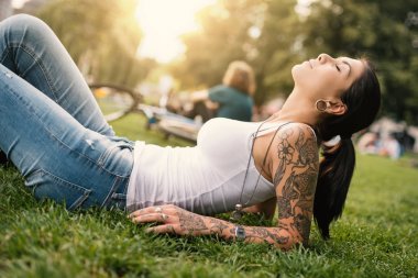 Genç esmer kadın Berlin, Almanya 'da bir parkta dinleniyor. Dizin