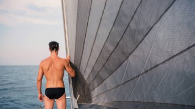 Yelkenli teknede denize bakan genç adam portresi. Buradan görüntüle