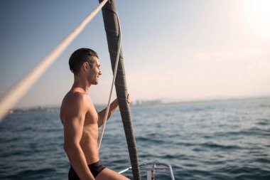 Young attractive man portrait on sailing boat at sunset. Real lifestyle image.