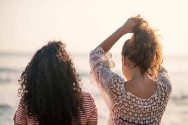 Genç kız kardeşler denizde portre çizerler, arkadan bakarlar. Yaşam tarzı kavramı.