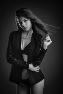 Siyah ceket giyen uzun saçlı şehvetli güzel kadın stüdyo portre. Siyah beyaz görüntü.