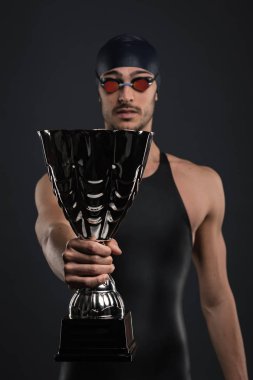 Koyu arka plan tutan fincan karşı Profesyonel atlet yüzücü stüdyo portre. Zafer kavramı.