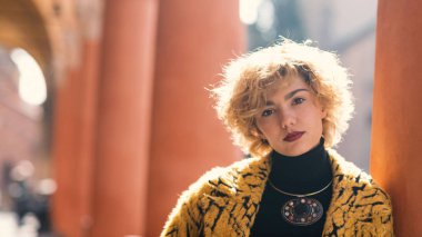 Blonde woman portrait outdoors in Piazza Santo Stefano, Bologna, Italy. Natual flare.